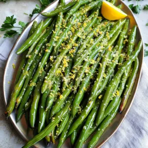 To make Air Fryer Parmesan Green Beans, you need these simple ingredients: - Fresh green beans - Extra virgin olive oil - Grated Parmesan cheese - Garlic powder - Onion powder - Smoked paprika - Sea salt and black pepper - Lemon zest Each ingredient plays an important role in this recipe. The fresh green beans bring a crisp texture and vibrant color. Extra virgin olive oil adds richness and helps the spices stick. Grated Parmesan cheese gives a savory flavor and crispy finish. Garlic powder and onion powder add depth and warmth. Smoked paprika provides a hint of smokiness. Sea salt and black pepper enhance all the flavors. Finally, lemon zest brightens the dish and adds a fresh note. Start by preheating your air fryer to 400°F (200°C). This step takes about 5 minutes. Preheating helps the green beans cook evenly and become crispy. Next, wash 1 pound of fresh green beans under cold water. Trim off the ends with a knife or kitchen scissors. After trimming, dry them with a paper towel. This removes extra moisture, which helps them crisp up nicely. In a large bowl, mix together 2 tablespoons of extra virgin olive oil, 1 teaspoon of garlic powder, 1 teaspoon of onion powder, 1/2 teaspoon of smoked paprika, and sea salt and black pepper to taste. Stir until all ingredients blend well. Add the prepared green beans to the bowl with the seasoning mix. Toss them well so every bean gets a nice coat. This step ensures all the flavors stick to the green beans. Then, sprinkle 1/2 cup of grated Parmesan cheese over the beans. Toss gently to distribute the cheese evenly. Now, place the coated green beans in the air fryer basket. Make sure they are in a single layer. Avoid overcrowding the basket for even cooking. Air fry the beans at 400°F (200°C) for 8-10 minutes. Halfway through, shake the basket gently to help with the crispiness. Once the green beans are crispy and golden brown, remove them from the air fryer. Garnish with fresh lemon zest for added brightness. Serve them on a colorful platter, topped with parsley. You can also add extra lemon wedges on the side for a zesty kick! To get your green beans super crispy, start by drying them well. After washing, use a paper towel to remove any water. The dryer they are, the better they crisp up in the air fryer. Preheat your air fryer to 400°F (200°C). This helps the beans cook evenly. A good tip is to cook them in a single layer. If they overlap, they won’t crisp as well. When you coat your green beans, use a large bowl. First, mix the olive oil and spices well. Then, add the beans to this mix. Toss them gently to coat each bean. Make sure to sprinkle the grated Parmesan cheese evenly. This way, every bite has that cheesy flavor. Don’t rush this step; take your time to coat them well. You can change up the seasoning to fit your taste! If you love heat, add red pepper flakes. Want a fresh twist? Use fresh herbs like thyme or basil. You can also swap smoked paprika for regular paprika if you prefer a milder flavor. Don’t be afraid to experiment! Just remember to keep the balance so that the green beans shine through. {{image_4}} You can change the cheese to mix up the flavor. Try using a mix of mozzarella and Parmesan for a gooey texture. If you want something sharper, consider aged cheddar. You can also use feta cheese for a tangy twist. Each cheese will add its unique taste to the green beans. Just remember, adjust the amount based on how strong you want the flavor. Spices can really change up your dish. If you enjoy a kick, add some cayenne pepper or chili powder. For a more earthy taste, try adding cumin or coriander. You can also switch the smoked paprika for regular paprika if you prefer a milder flavor. Experiment with different spices to find your favorite mix! Green beans are great, but feel free to try other veggies. Asparagus works well and cooks in the same time. Broccoli florets are another fantastic option; just cut them small. Carrots can also be air-fried, but cut them thin to ensure they cook evenly. Mixing different veggies can create a colorful and tasty dish! After cooking your crispy air fryer Parmesan green beans, let them cool to room temperature. This helps keep them crispy. Once cool, place them in an airtight container. Make sure to layer them with parchment paper to absorb moisture and keep them crunchy. Store the container in the fridge for best results. To reheat your green beans, use the air fryer again. Preheat it to 350°F (175°C). Place the beans in the basket and heat for about 3-5 minutes. This will help them regain their crispiness. You can also use a microwave, but be aware that they may lose their crunch. Cooked green beans will last in the fridge for about 3-4 days. If you want to keep them longer, consider freezing them. They can stay fresh in the freezer for up to 3 months. Just remember to thaw them in the fridge before reheating for the best texture. Yes, you can use frozen green beans. Just thaw them first and pat them dry. This steps helps in getting the best crisp. Cooking time may need to be adjusted. Start with 10 minutes and check for crispness. Air Fryer Parmesan Green Beans pair well with many dishes. Here are some ideas: - Grilled chicken - Salmon fillets - Quinoa salad - Pasta dishes - Tofu stir-fry These options bring balance and flavor to your meal. You’ll know the green beans are done when they turn golden brown and crispy. If you want, you can taste one to check the texture. They should be tender with a nice crunch. Yes! To make this dish vegan, skip the Parmesan cheese. Instead, try nutritional yeast for a cheesy flavor. You can also add more spices, like cumin or chili powder, for extra taste. You can experiment with various herbs and spices. Here are some tasty options: - Italian seasoning - Red pepper flakes - Thyme - Oregano - Dill Feel free to mix and match to find your favorite flavor profile! Now you know how to make crisp and tasty Air Fryer Parmesan Green Beans. We covered the great ingredients, easy steps, and tips for success. You can adjust the seasonings to match your taste. Feel free to add other veggies or cheeses for fun variations. Remember to store leftovers properly for the best taste later. I hope you enjoy making this dish. It’s quick, healthy, and perfect for any meal!