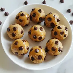 To make these tasty chocolate chip cookie dough protein balls, you will need: - 1 cup almond flour - 1/2 cup rolled oats - 1/4 cup vanilla protein powder - 1/4 cup almond butter (or any nut butter of your choice) - 1/4 cup honey or maple syrup - 1 teaspoon pure vanilla extract - 1/4 teaspoon salt - 1/2 cup mini chocolate chips - 2 tablespoons almond milk (or your preferred type of milk) These ingredients combine to create a delicious and nutritious snack. You can add extra flavors or textures to your protein balls. Here are some ideas: - Chopped nuts for crunch - Dried fruit for sweetness - A sprinkle of cinnamon for warmth - Flax seeds or chia seeds for added fiber These add-ins can boost flavor and nutrition. If you have specific dietary needs, here are some easy swaps: - Use peanut butter if you dislike almond butter. - For a vegan option, replace honey with maple syrup. - Swap almond flour with oat flour or coconut flour for gluten-free needs. - Use a plant-based protein powder for a vegan protein source. These substitutions keep the recipe flexible and enjoyable for everyone. {{ingredient_image_2}} Start by gathering your ingredients. In a large bowl, mix 1 cup of almond flour, 1/2 cup of rolled oats, and 1/4 cup of vanilla protein powder. Use a whisk or spoon to blend them well. Break up any clumps you see. Next, add 1/4 cup of almond butter and 1/4 cup of honey or maple syrup to the dry mix. Stir until the mixture is smooth and fully combined. Then, add 1 teaspoon of pure vanilla extract and 1/4 teaspoon of salt. Gently fold in 1/2 cup of mini chocolate chips and 2 tablespoons of almond milk. If the dough feels too dry, add more almond milk, one teaspoon at a time. Keep mixing until you get a nice, pliable dough. Now it's time to shape the dough into balls. Take about 1 tablespoon of the mixture in your hands. Roll it into a ball, making sure it is nice and firm. Place each ball on a parchment-lined baking sheet. Try to keep each ball about the same size. This makes them look great when served. Continue rolling until all the dough is used up. Once you&rsquo;ve shaped all the balls, cover the baking sheet with plastic wrap or a clean kitchen towel. Put them in the fridge for at least 30 minutes. This helps the protein balls firm up, giving them a better texture. After chilling, you can serve them right away. For a beautiful touch, arrange the balls on a decorative plate. Sprinkle a few extra mini chocolate chips around them for a fun look. If you want to be extra fancy, drizzle some almond butter over the top before serving. Enjoy your tasty, healthy snack! To get the best texture for your protein balls, start with the right flour. Almond flour gives a nice, nutty flavor and a soft texture. If the dough feels dry, add almond milk slowly. Just one teaspoon at a time helps. Mix until it holds together well. You want a dough that&rsquo;s easy to roll into balls without crumbling. These protein balls are great for snacks! To keep them fresh, store them in an airtight container. They last up to a week in the fridge. If you want to keep them longer, freeze them! Just layer them between parchment paper in a freezer-safe bag. They can last for about three months in the freezer. You can boost flavor and nutrition easily. Try adding a scoop of chia seeds or flaxseeds for extra fiber. Want a chocolate twist? Use dark chocolate chips instead of mini ones. If you like it sweeter, add more honey or maple syrup. Mix in some cinnamon or a pinch of sea salt to deepen the flavor. These small changes make your protein balls even better! Pro Tips Use Room Temperature Ingredients: Allow your almond butter and almond milk to come to room temperature for easier mixing and a smoother dough. Customize Your Protein Powder: Experiment with different flavors of protein powder, like chocolate or peanut butter, to add a unique twist to your protein balls. Store for Freshness: For optimal freshness, store your protein balls in an airtight container and consume within a week, or freeze them for longer storage. Add Textures: Incorporate nuts, seeds, or dried fruits into the mixture for additional texture and nutritional benefits. {{image_4}} You can switch up the flavor of your protein balls easily. Try using peanut butter instead of almond butter. It adds a rich taste and creamy texture. Coconut is another fun option. Just add shredded coconut to the mix for a tropical twist. You can also use different types of chocolate chips, like dark or white chocolate. Each choice brings a new taste to your snack. These protein balls can fit many diets. If you want a vegan option, swap the honey for maple syrup. This keeps it plant-based. Use a vegan protein powder to match. For a gluten-free treat, stick with gluten-free oats and almond flour. This way, you can enjoy the balls without worries about gluten. You can make simple swaps to change the nutrition. Use protein powder made from peas or brown rice to fit your needs. If you want more fiber, add chia seeds or flaxseeds. These tiny seeds pack a lot of health benefits. For a lower sugar option, cut down the honey or syrup. You can use stevia or monk fruit as a sweetener. These changes help you control your diet while enjoying a tasty treat. To keep your chocolate chip cookie dough protein balls fresh, store them in the fridge. Use an airtight container to prevent air from drying them out. They will stay good for about a week. Always check for any signs of spoilage before eating. If you want to save some for later, freezing is a great option. Place the protein balls in a single layer on a baking sheet. Freeze them for about an hour until firm. Then, transfer them to a freezer-safe bag or container. They can last up to three months in the freezer. Just thaw them in the fridge overnight before enjoying. Use clear containers to store your protein balls. This way, you can see what's inside at a glance. Label each container with the date you made the protein balls. This helps you track freshness. You can even add a note about the flavor or any special ingredients you used. Yes, you can make these protein balls vegan. Replace honey with maple syrup. Use a plant-based protein powder. Almond butter is already vegan, so you&rsquo;re good there! These protein balls last about one week in the fridge. Store them in an airtight container. If you want them to last longer, freeze them! Almond flour adds healthy fats and protein. It is lower in carbs than regular flour. This makes it great for energy and keeping you full. Plus, it gives a nice flavor and texture to your protein balls. We covered a lot about protein balls. You learned the main ingredients, optional add-ins, and substitutions for diets. I shared step-by-step instructions for mixing, shaping, and serving. Tips for perfecting texture and storing helped you enhance flavor. We also explored yummy variations and proper storage methods. Remember, you can make these protein balls fit your needs. Enjoy making and sharing them!