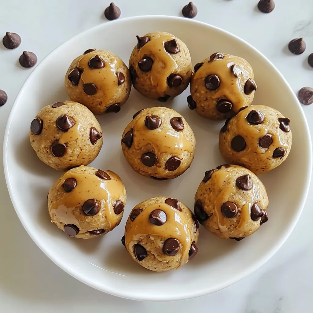 To make these tasty chocolate chip cookie dough protein balls, you will need: - 1 cup almond flour - 1/2 cup rolled oats - 1/4 cup vanilla protein powder - 1/4 cup almond butter (or any nut butter of your choice) - 1/4 cup honey or maple syrup - 1 teaspoon pure vanilla extract - 1/4 teaspoon salt - 1/2 cup mini chocolate chips - 2 tablespoons almond milk (or your preferred type of milk) These ingredients combine to create a delicious and nutritious snack. You can add extra flavors or textures to your protein balls. Here are some ideas: - Chopped nuts for crunch - Dried fruit for sweetness - A sprinkle of cinnamon for warmth - Flax seeds or chia seeds for added fiber These add-ins can boost flavor and nutrition. If you have specific dietary needs, here are some easy swaps: - Use peanut butter if you dislike almond butter. - For a vegan option, replace honey with maple syrup. - Swap almond flour with oat flour or coconut flour for gluten-free needs. - Use a plant-based protein powder for a vegan protein source. These substitutions keep the recipe flexible and enjoyable for everyone. {{ingredient_image_2}} Start by gathering your ingredients. In a large bowl, mix 1 cup of almond flour, 1/2 cup of rolled oats, and 1/4 cup of vanilla protein powder. Use a whisk or spoon to blend them well. Break up any clumps you see. Next, add 1/4 cup of almond butter and 1/4 cup of honey or maple syrup to the dry mix. Stir until the mixture is smooth and fully combined. Then, add 1 teaspoon of pure vanilla extract and 1/4 teaspoon of salt. Gently fold in 1/2 cup of mini chocolate chips and 2 tablespoons of almond milk. If the dough feels too dry, add more almond milk, one teaspoon at a time. Keep mixing until you get a nice, pliable dough. Now it's time to shape the dough into balls. Take about 1 tablespoon of the mixture in your hands. Roll it into a ball, making sure it is nice and firm. Place each ball on a parchment-lined baking sheet. Try to keep each ball about the same size. This makes them look great when served. Continue rolling until all the dough is used up. Once you’ve shaped all the balls, cover the baking sheet with plastic wrap or a clean kitchen towel. Put them in the fridge for at least 30 minutes. This helps the protein balls firm up, giving them a better texture. After chilling, you can serve them right away. For a beautiful touch, arrange the balls on a decorative plate. Sprinkle a few extra mini chocolate chips around them for a fun look. If you want to be extra fancy, drizzle some almond butter over the top before serving. Enjoy your tasty, healthy snack! To get the best texture for your protein balls, start with the right flour. Almond flour gives a nice, nutty flavor and a soft texture. If the dough feels dry, add almond milk slowly. Just one teaspoon at a time helps. Mix until it holds together well. You want a dough that’s easy to roll into balls without crumbling. These protein balls are great for snacks! To keep them fresh, store them in an airtight container. They last up to a week in the fridge. If you want to keep them longer, freeze them! Just layer them between parchment paper in a freezer-safe bag. They can last for about three months in the freezer. You can boost flavor and nutrition easily. Try adding a scoop of chia seeds or flaxseeds for extra fiber. Want a chocolate twist? Use dark chocolate chips instead of mini ones. If you like it sweeter, add more honey or maple syrup. Mix in some cinnamon or a pinch of sea salt to deepen the flavor. These small changes make your protein balls even better! Pro Tips Use Room Temperature Ingredients: Allow your almond butter and almond milk to come to room temperature for easier mixing and a smoother dough. Customize Your Protein Powder: Experiment with different flavors of protein powder, like chocolate or peanut butter, to add a unique twist to your protein balls. Store for Freshness: For optimal freshness, store your protein balls in an airtight container and consume within a week, or freeze them for longer storage. Add Textures: Incorporate nuts, seeds, or dried fruits into the mixture for additional texture and nutritional benefits. {{image_4}} You can switch up the flavor of your protein balls easily. Try using peanut butter instead of almond butter. It adds a rich taste and creamy texture. Coconut is another fun option. Just add shredded coconut to the mix for a tropical twist. You can also use different types of chocolate chips, like dark or white chocolate. Each choice brings a new taste to your snack. These protein balls can fit many diets. If you want a vegan option, swap the honey for maple syrup. This keeps it plant-based. Use a vegan protein powder to match. For a gluten-free treat, stick with gluten-free oats and almond flour. This way, you can enjoy the balls without worries about gluten. You can make simple swaps to change the nutrition. Use protein powder made from peas or brown rice to fit your needs. If you want more fiber, add chia seeds or flaxseeds. These tiny seeds pack a lot of health benefits. For a lower sugar option, cut down the honey or syrup. You can use stevia or monk fruit as a sweetener. These changes help you control your diet while enjoying a tasty treat. To keep your chocolate chip cookie dough protein balls fresh, store them in the fridge. Use an airtight container to prevent air from drying them out. They will stay good for about a week. Always check for any signs of spoilage before eating. If you want to save some for later, freezing is a great option. Place the protein balls in a single layer on a baking sheet. Freeze them for about an hour until firm. Then, transfer them to a freezer-safe bag or container. They can last up to three months in the freezer. Just thaw them in the fridge overnight before enjoying. Use clear containers to store your protein balls. This way, you can see what's inside at a glance. Label each container with the date you made the protein balls. This helps you track freshness. You can even add a note about the flavor or any special ingredients you used. Yes, you can make these protein balls vegan. Replace honey with maple syrup. Use a plant-based protein powder. Almond butter is already vegan, so you’re good there! These protein balls last about one week in the fridge. Store them in an airtight container. If you want them to last longer, freeze them! Almond flour adds healthy fats and protein. It is lower in carbs than regular flour. This makes it great for energy and keeping you full. Plus, it gives a nice flavor and texture to your protein balls. We covered a lot about protein balls. You learned the main ingredients, optional add-ins, and substitutions for diets. I shared step-by-step instructions for mixing, shaping, and serving. Tips for perfecting texture and storing helped you enhance flavor. We also explored yummy variations and proper storage methods. Remember, you can make these protein balls fit your needs. Enjoy making and sharing them!